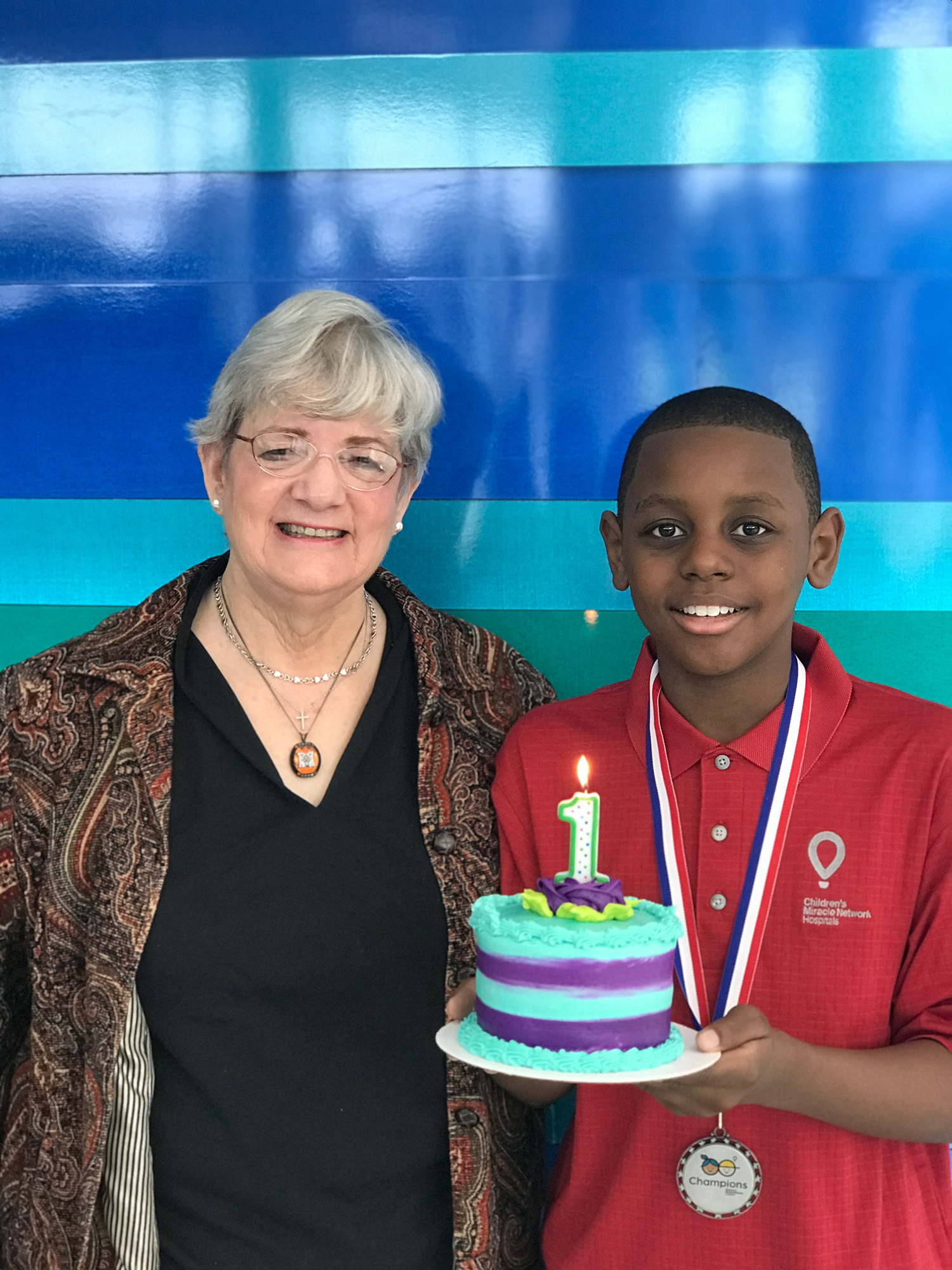 Beverly Bryan Thompson stands beside a boy holding a birthday cake